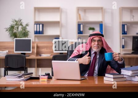 Gealterter arabischer Angestellter, der während der Pause Kaffee trinkt Stockfoto