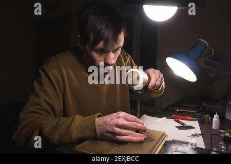 Löcher in Leder mit Locherwerkzeug machen. Stockfoto