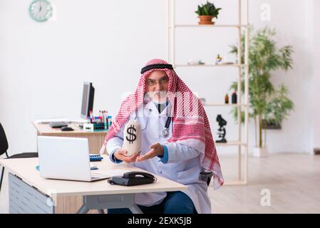 Erfahrene männliche arabische Arzt hält Geldbeutel Stockfoto