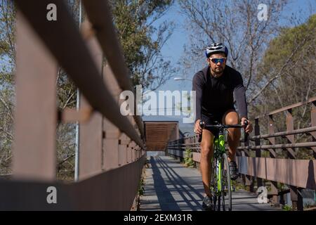 Ein hispanischer Mann in einem Sportanzug, der ein Fahrrad fährt In einer Stadt Stockfoto