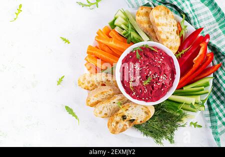 Gerösteter Rübenhummus mit Toast und Gemüse auf hellem Hintergrund. Beetroot Hummus. Draufsicht, oben, Kopierbereich Stockfoto