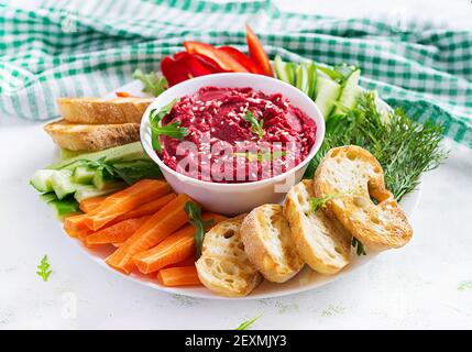 Gerösteter Rübenhummus mit Toast und Gemüse auf hellem Hintergrund. Beetroot Hummus. Stockfoto