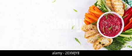 Gerösteter Rübenhummus mit Toast und Gemüse auf hellem Hintergrund. Beetroot Hummus. Draufsicht, oben, Banner Stockfoto