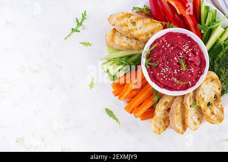 Gerösteter Rübenhummus mit Toast und Gemüse auf hellem Hintergrund. Beetroot Hummus. Draufsicht, oben, Kopierbereich Stockfoto