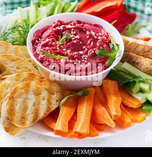 Gerösteter Rübenhummus mit Toast und Gemüse auf hellem Hintergrund. Beetroot Hummus. Stockfoto