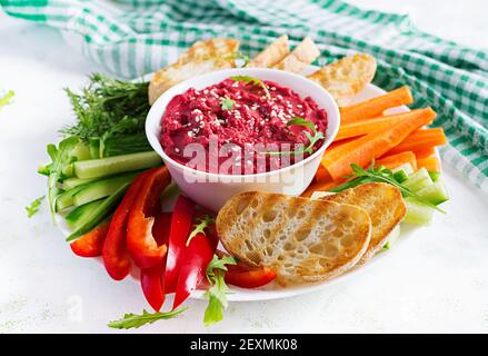 Gerösteter Rübenhummus mit Toast und Gemüse auf hellem Hintergrund. Beetroot Hummus. Stockfoto