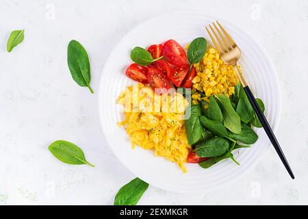 Frühstück. Rührei mit Kirschtomaten, Spinat und Mais. Draufsicht, flach liegend, oben Stockfoto