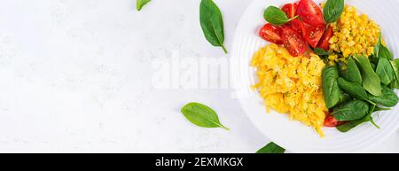 Frühstück. Rührei mit Kirschtomaten, Spinat und Mais. Draufsicht, Banner Stockfoto