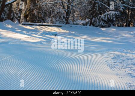 Die Geometrie der Pistenlinien auf der Skipiste, links von der Schneekatze aus flachen Streifen. Stockfoto