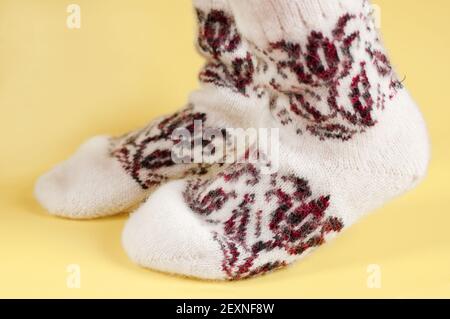 Kinderfüße in Wollsocken auf gelbem Hintergrund Stockfoto