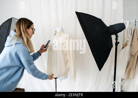 Circular Economy, aus zweiter Hand, Fast Fashion, Nachhaltige Mode. Shop-Besitzer machen Bilder von Second Hand Kleidung für Online-Shop Verkauf. Stockfoto