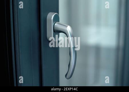 Stilvoller Chromgriff auf dunklem Fensterrahmen. Stockfoto