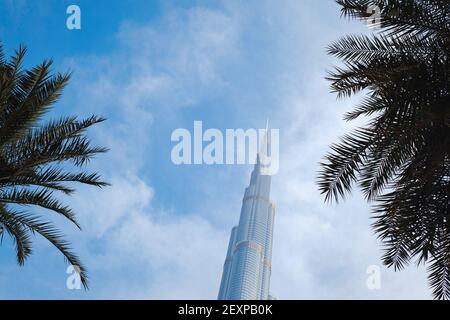 DUBAI, VEREINIGTE ARABISCHE EMIRATE - 10. FEBRUAR 2021: Bottom-up-Ansicht des Burj Khalifa im Kontrast zum blauen Himmel und den Wolken. Am unteren Ende des Gebäudes Stockfoto