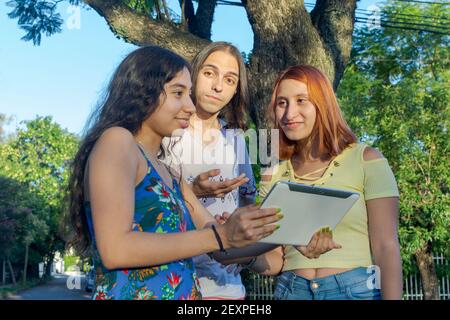 Eine schöne Aufnahme von drei jungen Erwachsenen mit einem freundlichen Gespräch, während Sie an einem Tablet festhalten Stockfoto