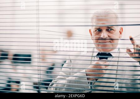 Nahaufnahme: Seriöser Business man steht vor dem Bürofenster Stockfoto