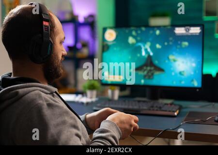 Videogamer spielen Grafik Cyberspace sitzen auf Gaming-Stuhl mit Technologie Netzwerk Wireless. Mann Streaming virale Videospiele zum Spaß mit Kopfhörern und Joystick für Online-Meisterschaft Stockfoto