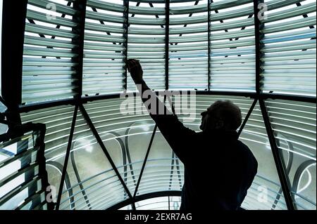 Happisburgh Lighthouse, Norfolk, 6th. Februar 2021 Patrick Tubby, Chairman des Happisburgh Lighthouse Trust, der die Lampe 500W und die Glasprismen, die original aus dem Jahr 1860 im Inneren der Fresnel-Linse sind, reinigt. Happisburgh Lighthouse an der Nordnorfolk-Küste ist der einzige unabhängig betriebene Leuchtturm in Großbritannien. Es ist auch der älteste funktionierende Leuchtturm in East Anglia. Fotografie von Jason Bye t: 07966 173 930 e: mail@jasonbye.com w: http://www.jasonbye.com Stockfoto