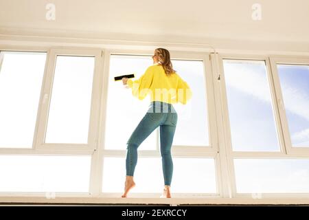 Horizontale Ansicht Hausfrau wäscht Fenster, während sie auf der Fensterbank steht Konzept der Sauberkeit und Sterilität im Haus Wohnung Reinigung Stockfoto