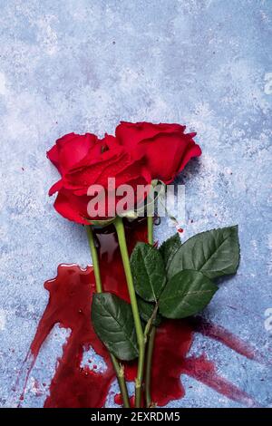 Rote Rosen und Blut auf einem blauen texturierten Hintergrund mit Platz für Text und Text Stockfoto