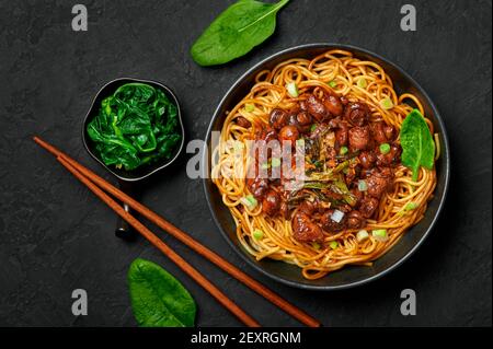 Bakmi oder Mie Ayam in schwarzer Schale auf dunkler Schieferplatte. Indonesische Küche Nudeln Fleischgericht. Traditionelles asiatisches Essen und Essen. Draufsicht Stockfoto