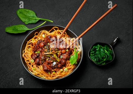 Bakmi oder Mie Ayam in schwarzer Schale auf dunkler Schieferplatte. Indonesische Küche Nudeln Fleischgericht. Traditionelles asiatisches Essen und Essen. Stockfoto