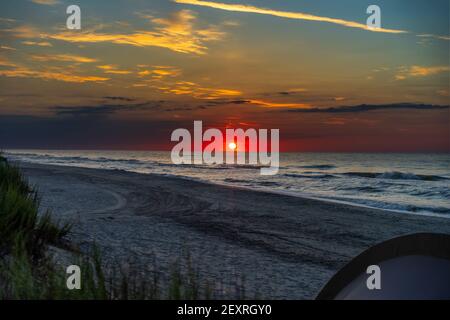 Panoramablick auf schönen roten Sonnenaufgang an der Küste und Camping Zelt am Strand am Sommermorgen. Stockfoto