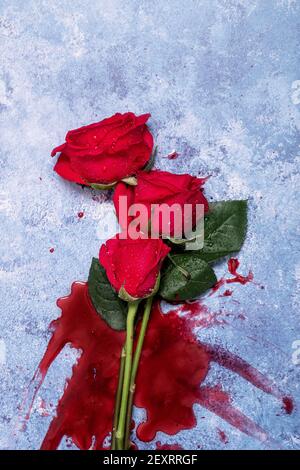 Rote Rosen und Blut auf einem blauen texturierten Hintergrund mit Platz für Text und Text Stockfoto