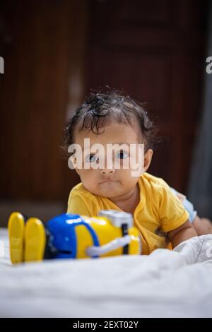 Kind in gelbem Kleid spielen mit Minons Spielzeug durch liegen Auf dem Boden Stockfoto