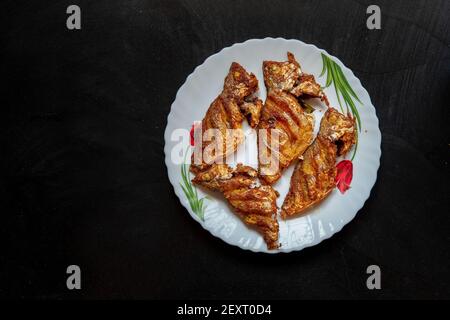 Kerala Stil würzigen Fisch braten auf einem weißen Teller in Schwarzer Hintergrund Stockfoto