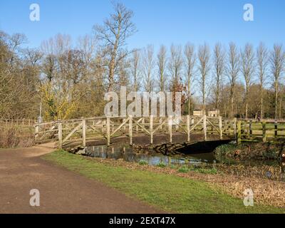 Hölzerne Fußgängerbrücke über den Fluss Tove an einem kalten, aber sonnigen Wintertag, Towcester, Northamptonshire, Großbritannien Stockfoto