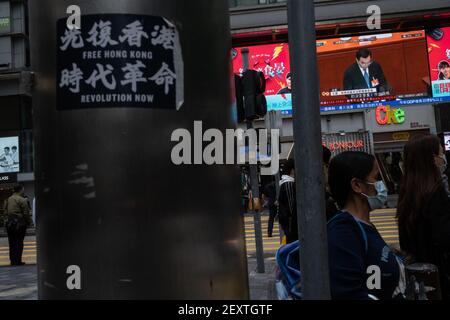 Ein großer Fernsehbildschirm im Tsim Sha Tsui Bezirk sendet den Nachrichtenbericht von Wang Chen, dem stellvertretenden Vorsitzenden des Ständigen Ausschusses des Nationalen Volkskongresses (NPC), der während der Eröffnungszeremonie des Kongresses eine Rede hält. Bei der Eröffnungssitzung des Nationalen Volkskongresses wurden Pläne angekündigt, das Wahlsystem Hongkongs zu überarbeiten, um sicherzustellen, dass „Patrioten“ die Verantwortung tragen. Stockfoto