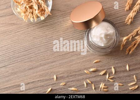 Natürliche feuchtigkeitsspendende Creme mit Haferextrakt im Glas auf Holztisch mit Spikes Draufsicht Stockfoto