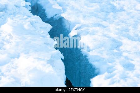 Großer sauberer Riss im Meereis mit weißem Schnee auf der Oberseite. Stockfoto