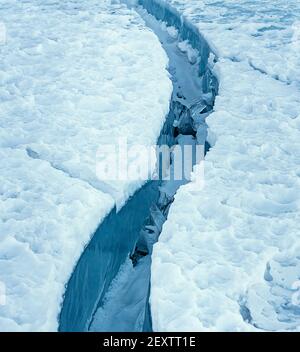 Großer sauberer Riss im Meereis mit weißem Schnee auf der Oberseite. Stockfoto