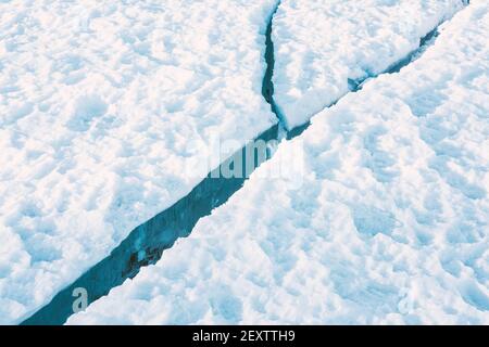 Großer sauberer Riss im Meereis mit weißem Schnee auf der Oberseite. Stockfoto