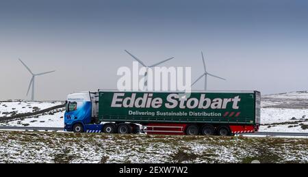 Auf der Autobahn M6 fahren Waggons Richtung Süden durch Cumbria bei der Kreuzung 37, im Hintergrund der Windpark Lambriggs. Cumbria, Großbritannien. Stockfoto