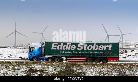 Auf der Autobahn M6 fahren Waggons Richtung Süden durch Cumbria bei der Kreuzung 37, im Hintergrund der Windpark Lambriggs. Cumbria, Großbritannien. Stockfoto