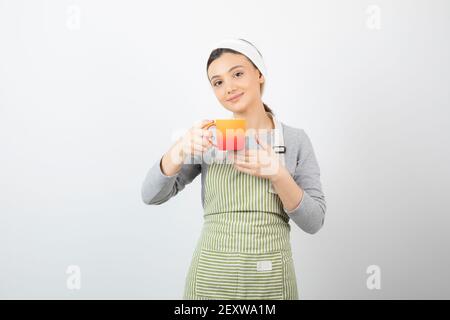 Bild einer hübschen jungen Frau in Schürze mit einem becher Stockfoto