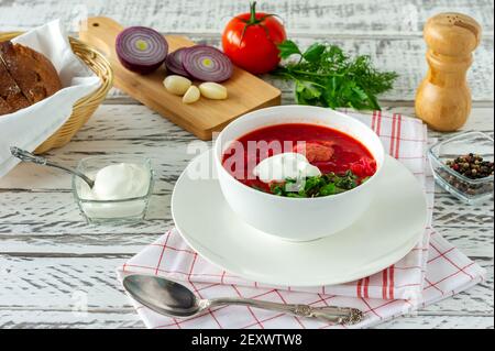 Traditionelles ukrainisches russisches Borscht mit Knoblauch und Brot. Eine Schüssel rote Rote Beete borscht auf einem weißen Holztisch. Rote Beete Suppe. Traditionell slawisch Stockfoto