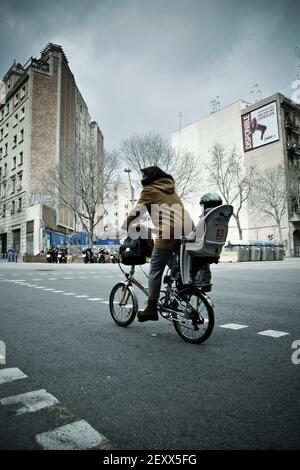 Rückansicht einer Mutter mit ihrem Sohn auf dem Rücksitz eines Fahrrads auf einer Straße. Stockfoto