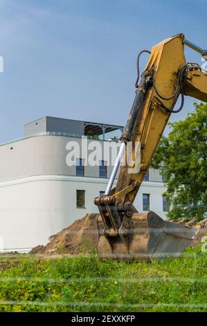 POZNAN, POLEN - 11. Sep 2017: Gelber Bagger vor einem neuen Mehrfamilienhaus auf einer Baustelle Stockfoto