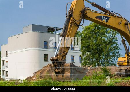 POZNAN, POLEN - 11. Sep 2017: Gelber Bagger vor einem neuen Mehrfamilienhaus auf einer Baustelle Stockfoto