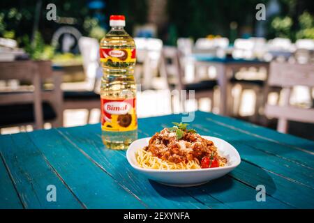 BRCKO, BOSNIEN UND HERZEGOWINA - 03. Jul 2019: Flasche Öl mit leckerem Essen auf dem Tisch im Garten Stockfoto
