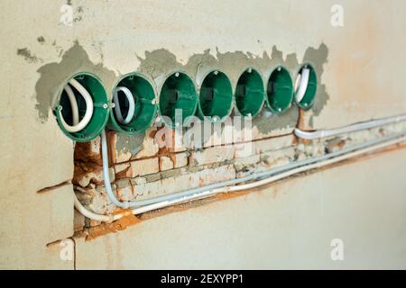 Neue Elektroinstallation, Kunststoffkästen und Stromkabel für zukünftige Steckdosen an der Wand, Sanierungskonzept. Stockfoto