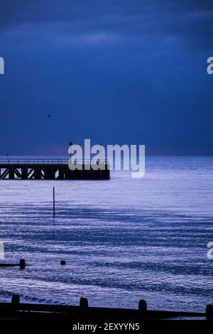 Old Barge Pier im Gunners Park, Thames Estuary, Shoeburyness. Before Dawn das reflektierte Licht gibt dem Meer einen Silbernen Sheen gegen eine Deep Blue Bank Stockfoto