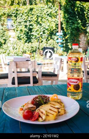 BRCKO, BOSNIEN UND HERZEGOWINA - 03. Jul 2019: Flasche Öl mit leckerem Essen auf dem Tisch im Garten Stockfoto
