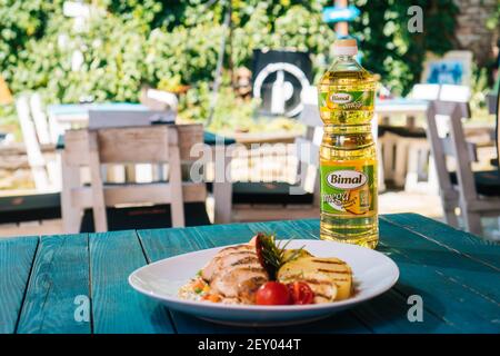 BRCKO, BOSNIEN UND HERZEGOWINA - 03. Jul 2019: Flasche Öl mit leckerem Essen auf dem Tisch im Garten Stockfoto
