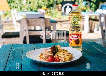 BRCKO, BOSNIEN UND HERZEGOWINA - 03. Jul 2019: Flasche Öl mit leckerem Essen auf dem Tisch im Garten Stockfoto