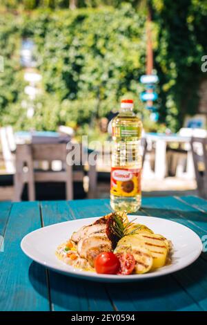 BRCKO, BOSNIEN UND HERZEGOWINA - 03. Jul 2019: Flasche Öl mit leckerem Essen auf dem Tisch im Garten Stockfoto