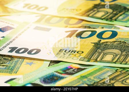 Haufen von europäischem Geld in hellem Sonnenlicht. 100 Euro Hintergrund. Stockfoto